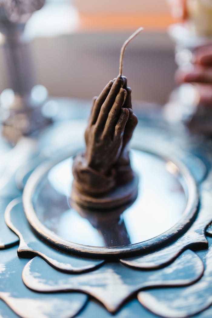 services-03 Handcrafted candle shaped like praying hands on a reflective surface, perfect for inspiration or spiritual ambiance.